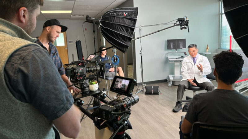 Film crew recording an interview with a doctor in a clinic office
