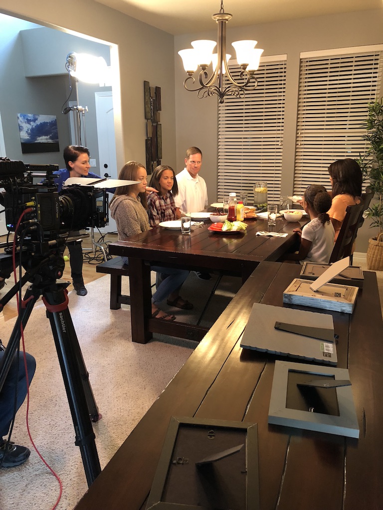 Cinema camera on a tripod filming a family dinner scene for Where Food Comes From, lit by a soft key light